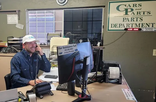 Loren Huskey at the CAP parts counter, on the phone under the Parts Department sign