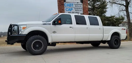 A white six-door Ford pickup parked in front of the CABT and CAP road sign at 4514 S Division