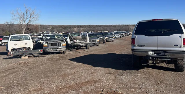 A long row of Ford Super Duty trucks and an Excursion in the yard