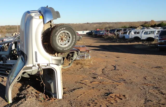 Vehicles being dismantled in the salvage yard on red Oklahoma dirt
